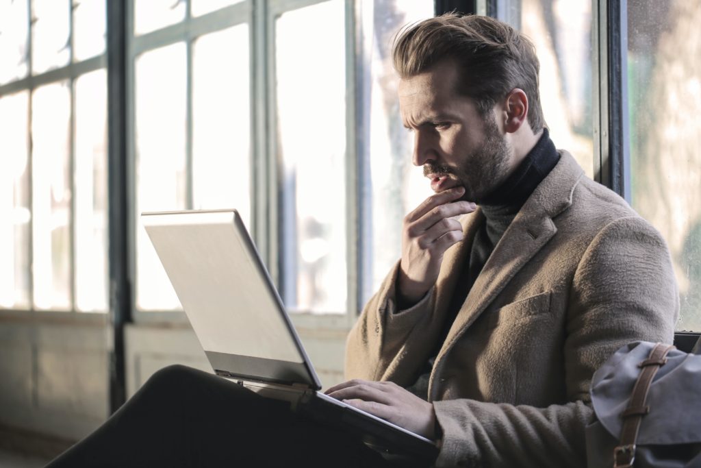 Man searching for answers on his laptop looking puzzled